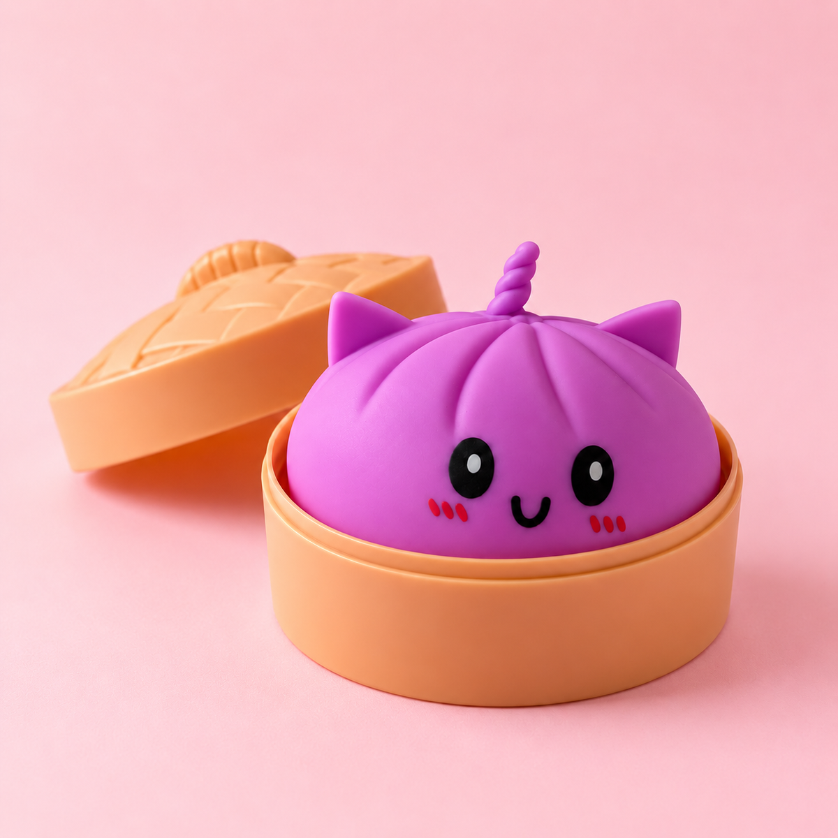 Squishy bao kawaii violet avec oreilles de chat et corne de licorne dans son panier vapeur, fond rose