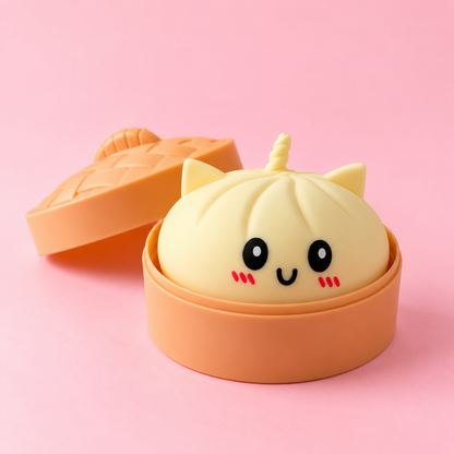 Squishy bao kawaii crème avec oreilles de chat et corne de licorne dans son panier vapeur, fond rose